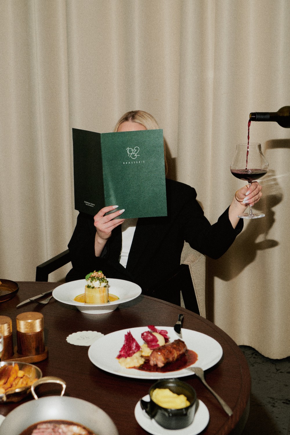 Femme au restaurant, vin rouge servi à table
