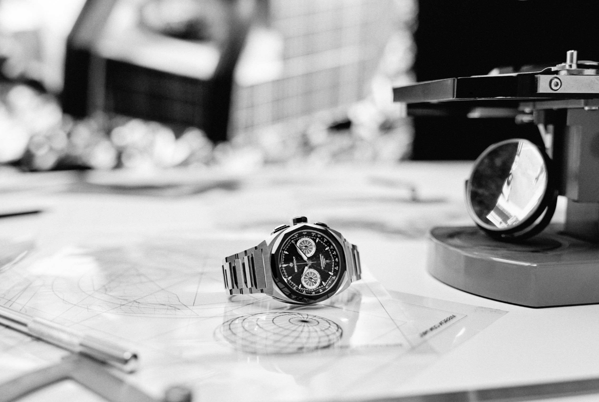 Montre chronographe posée sur plans techniques d’horlogerie