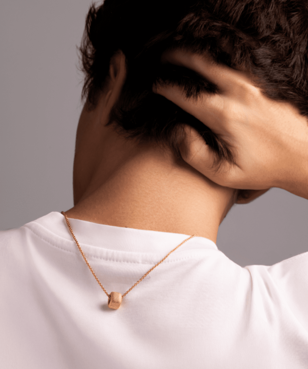 Personne touchant sa nuque avec collier en or