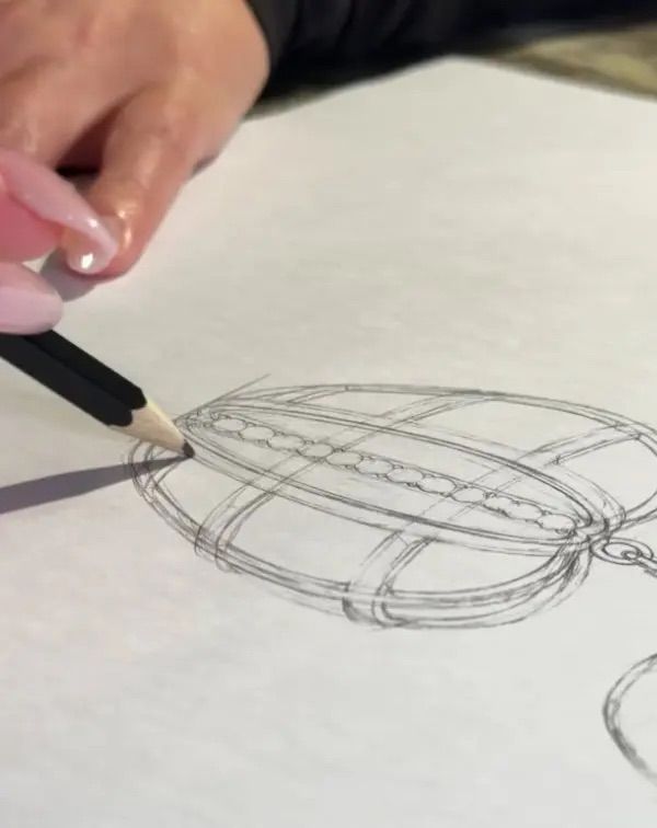 Main dessinant au crayon une sandale sur papier