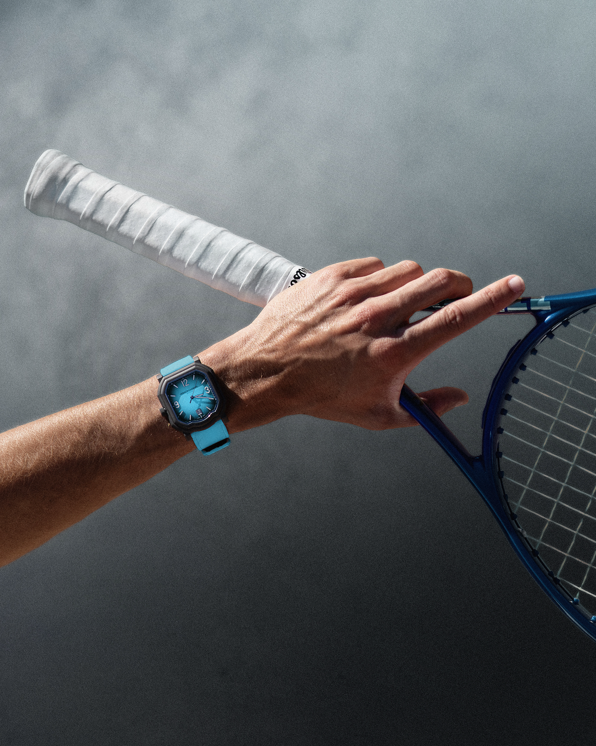 Main portant raquette de tennis et montre bleue