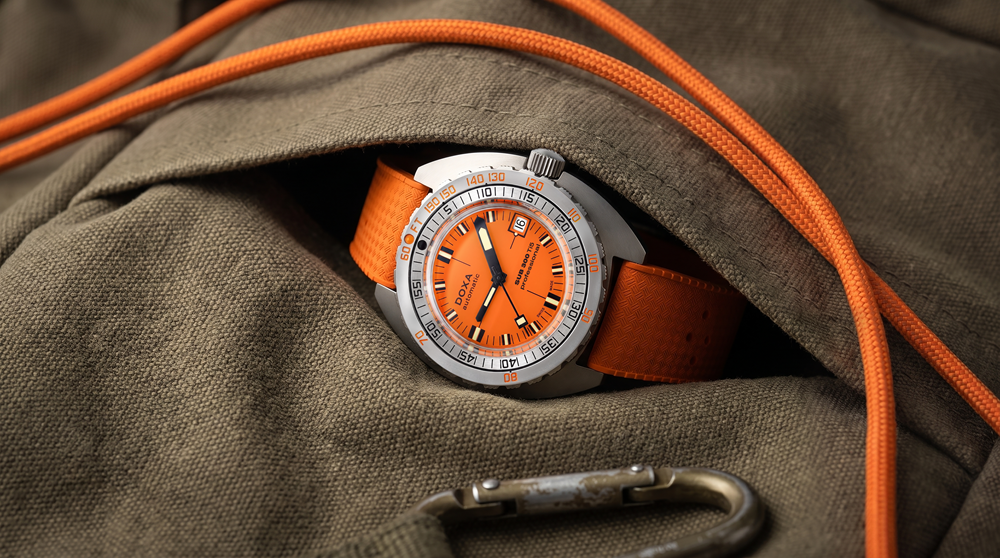 Montre de plongée orange posée sur un sac kaki