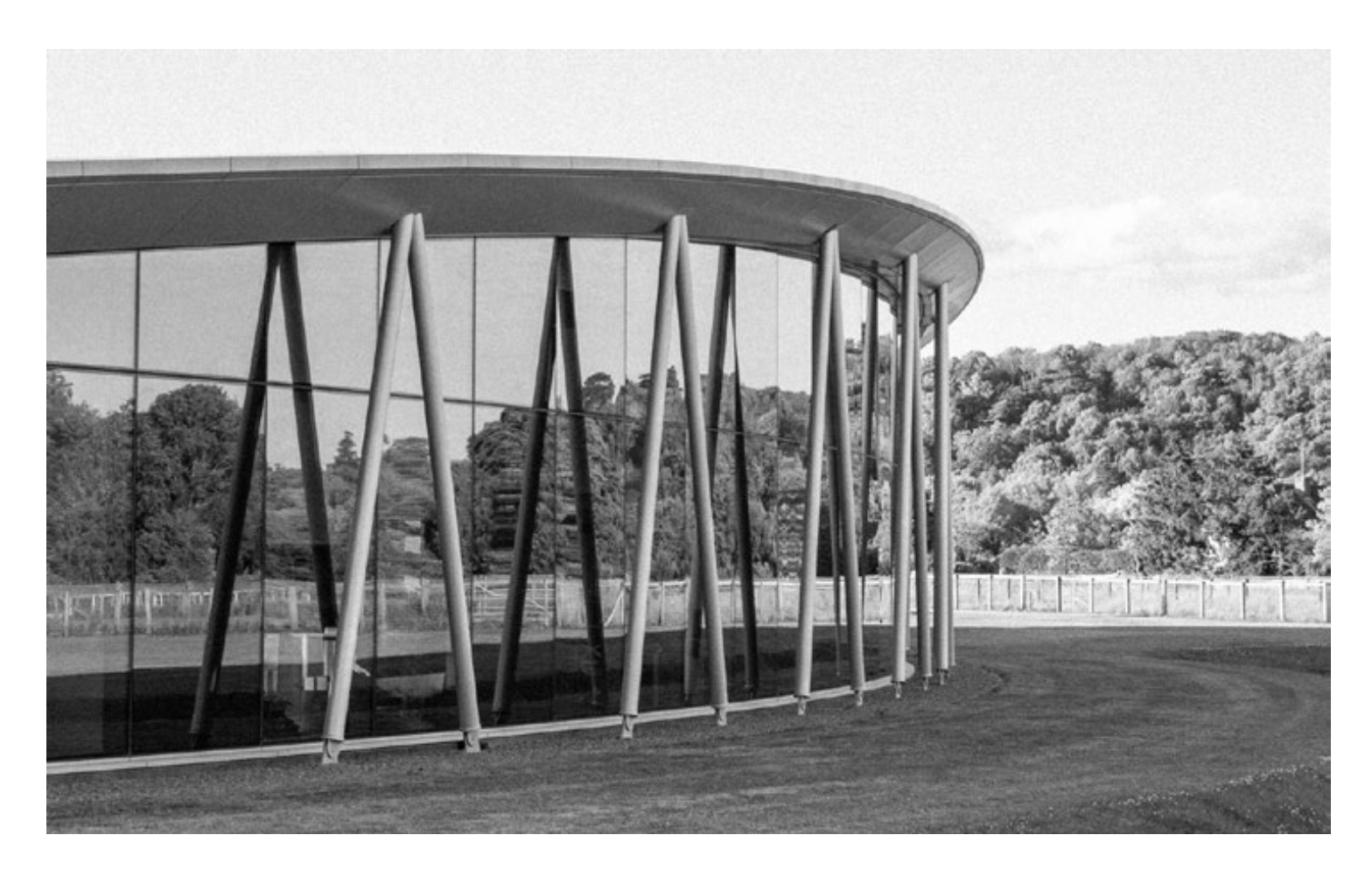 Pavillon moderne vitré aux colonnes inclinées dans un parc