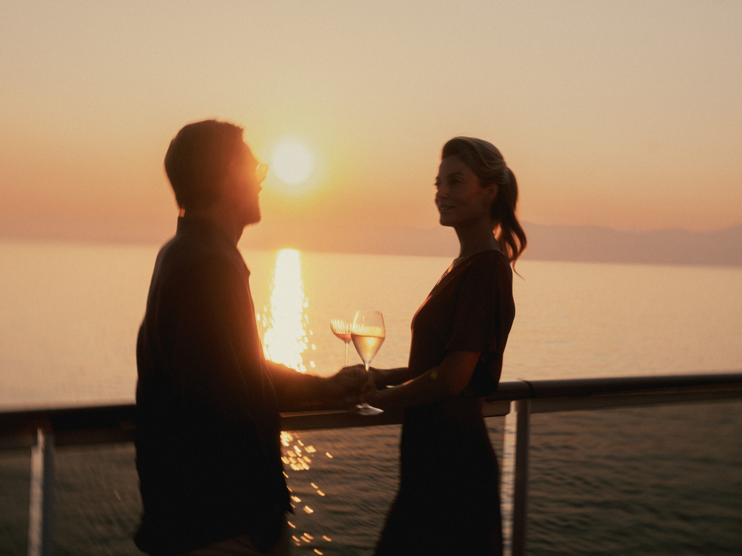 Couple au coucher du soleil avec verres de vin