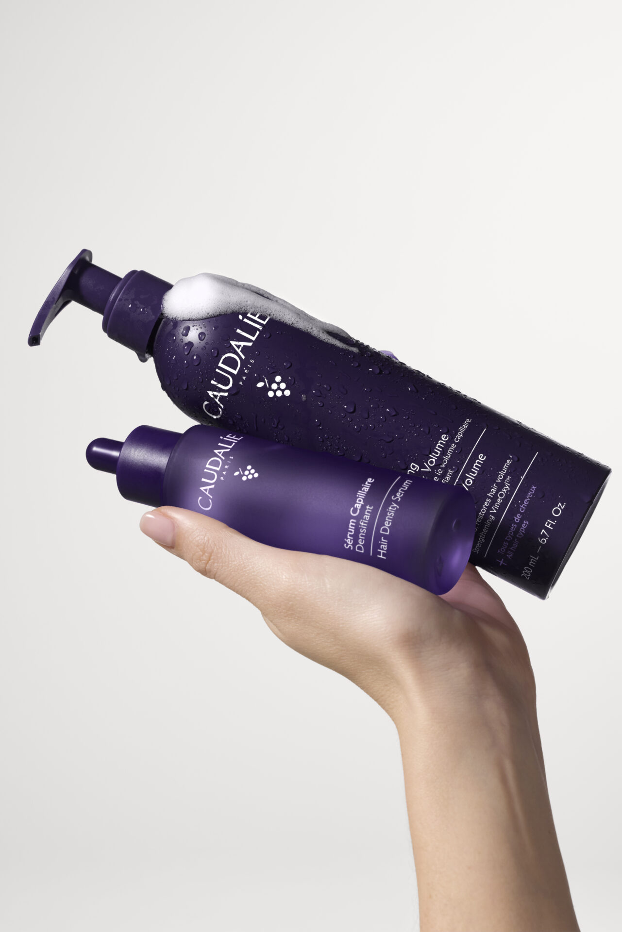 Produits capillaires Caudalie violets tenus à la main