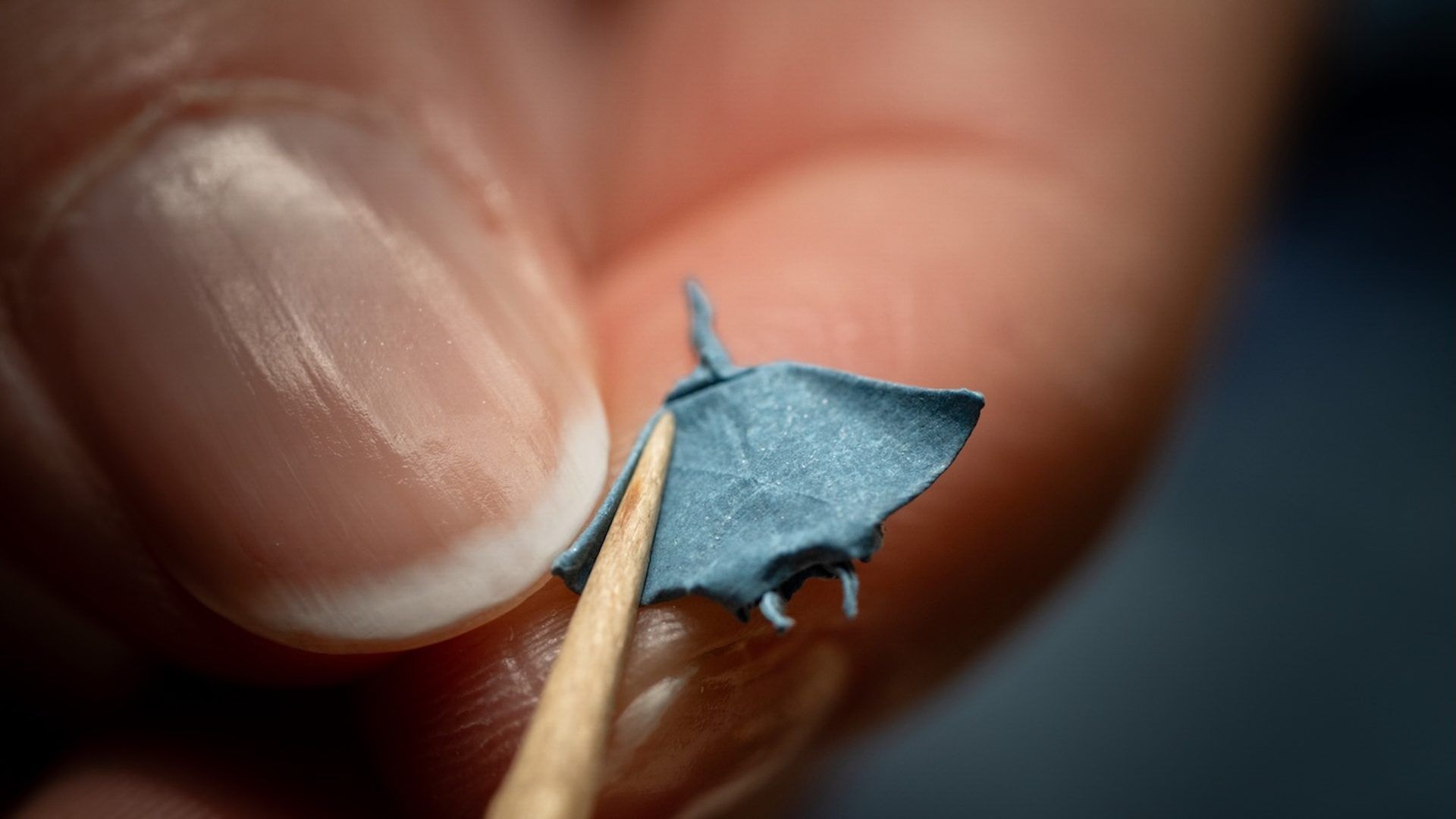 Minuscule parapluie en papier tenu entre deux doigts