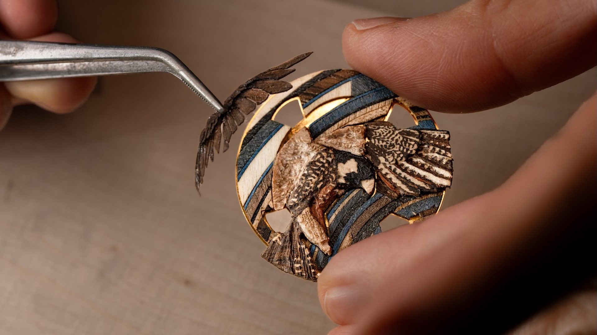 Artisan assemblant des ailes d’insectes sur un bijou