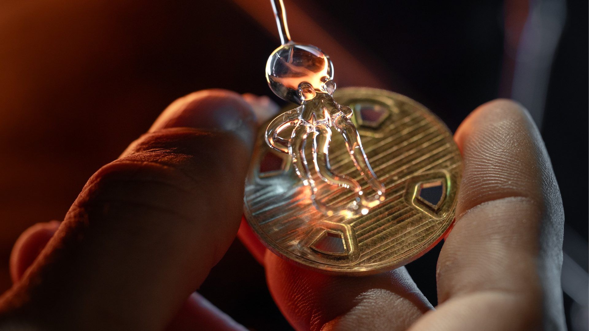 Artisan façonnant une figurine de verre sur une médaille