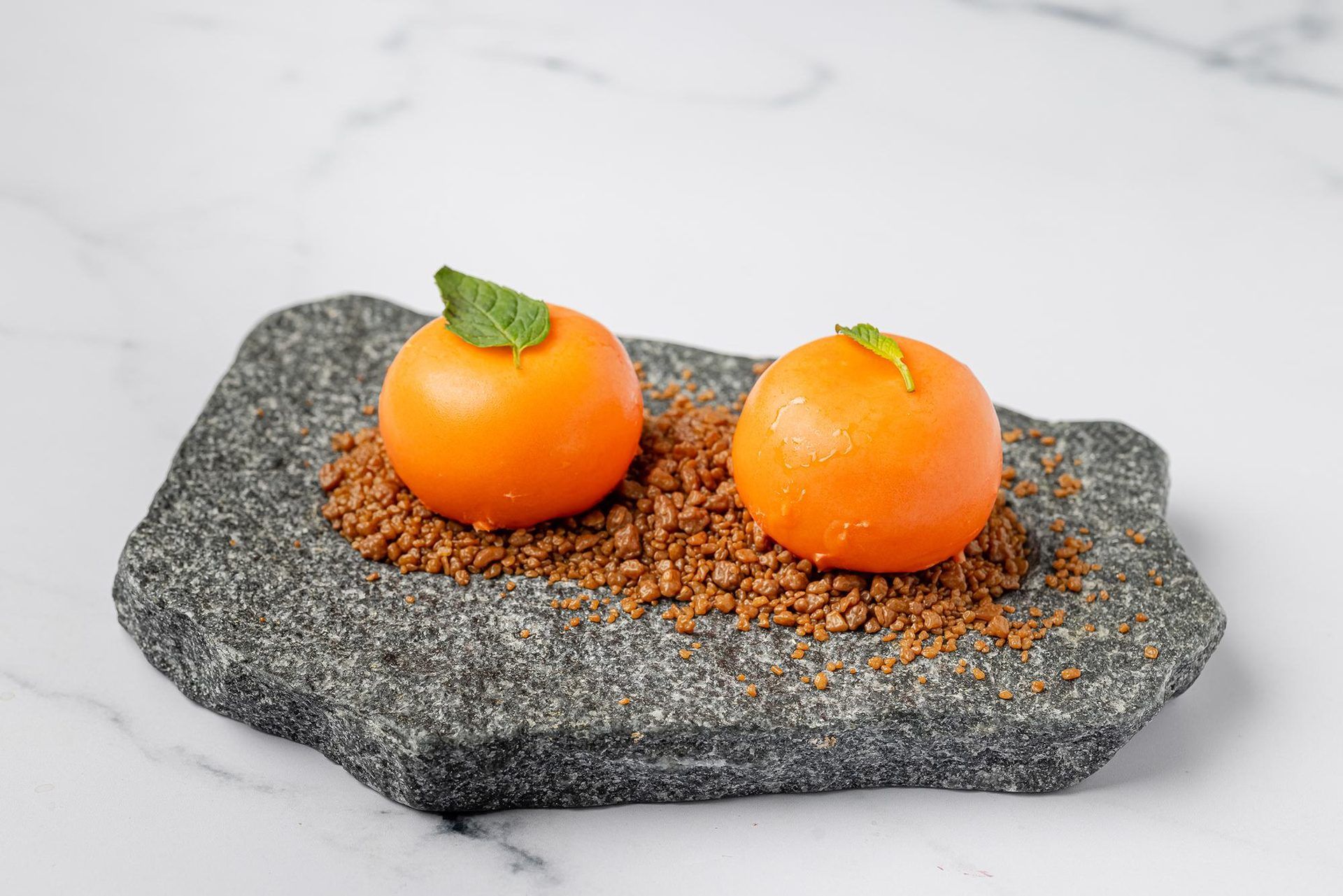 Deux sphères orangées sur crumble, décorées de menthe