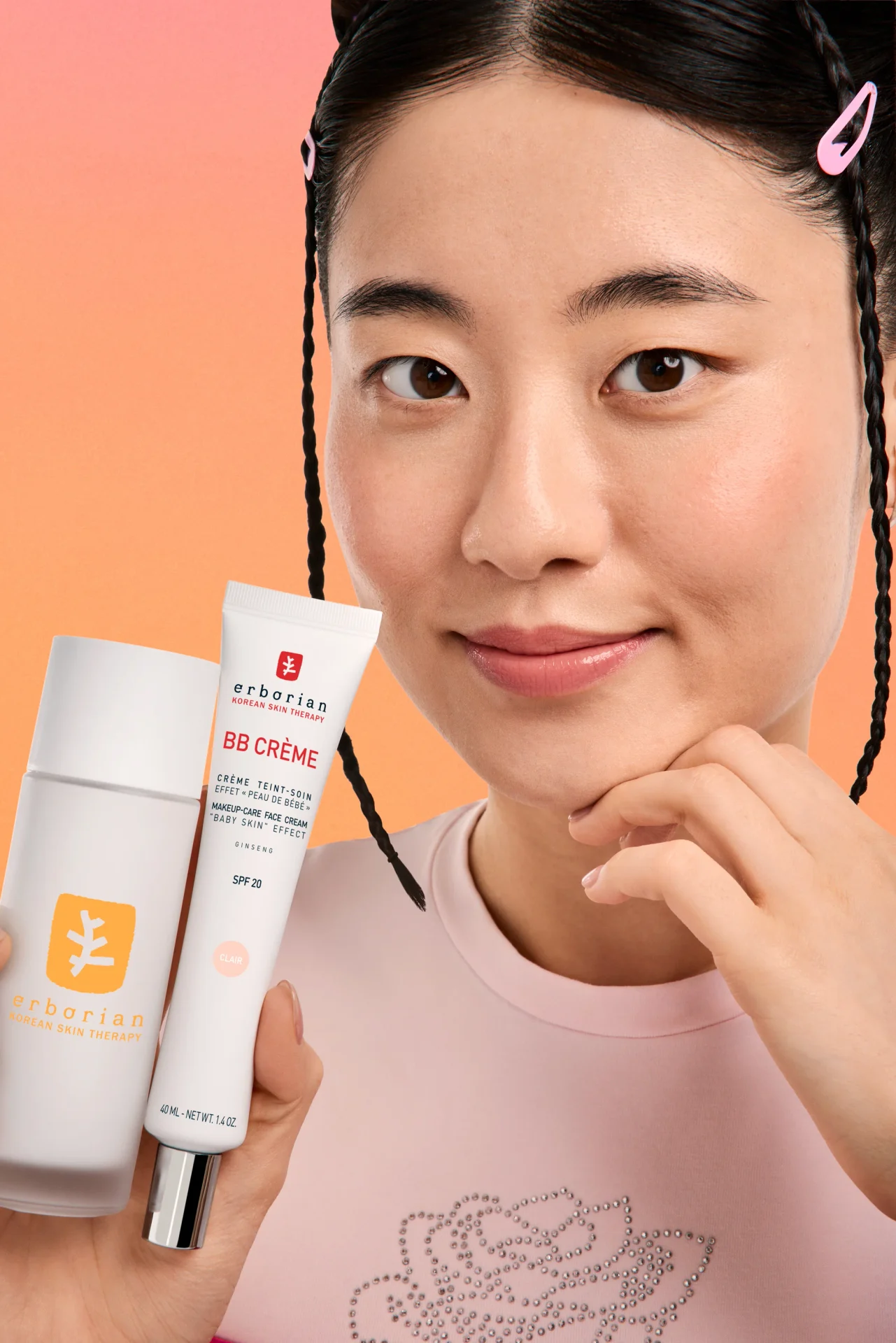 Femme présentant la BB Crème Erborian sur fond corail