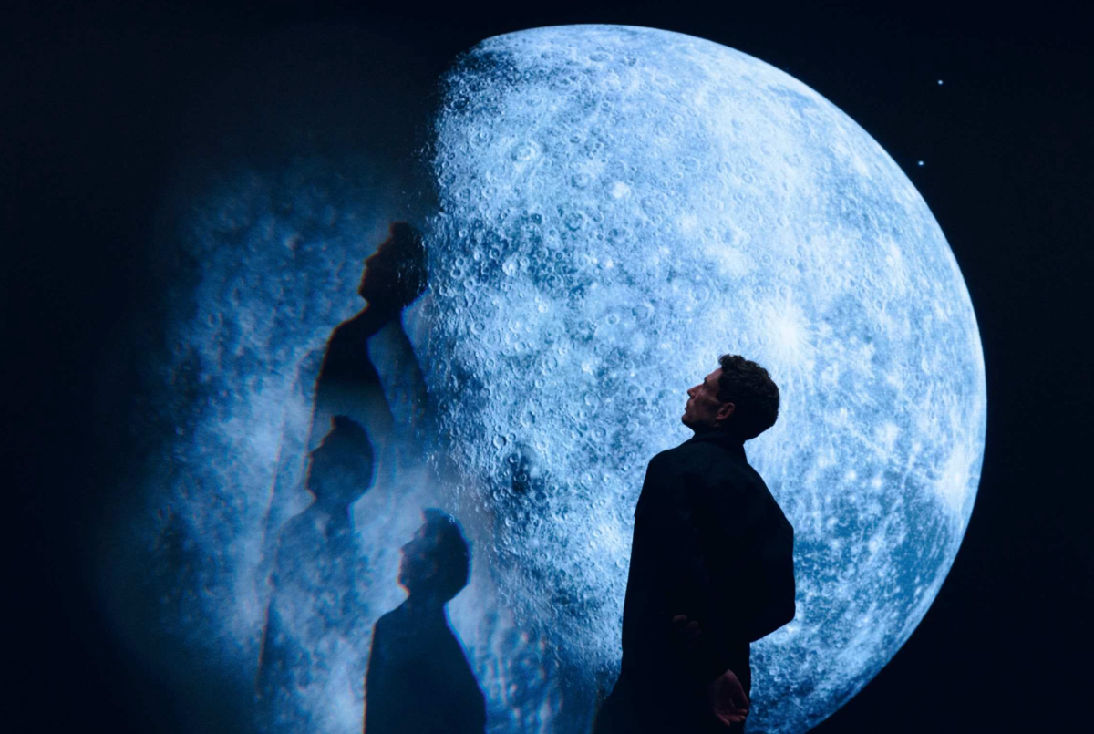 Homme contemplant une immense lune bleutée avec reflets