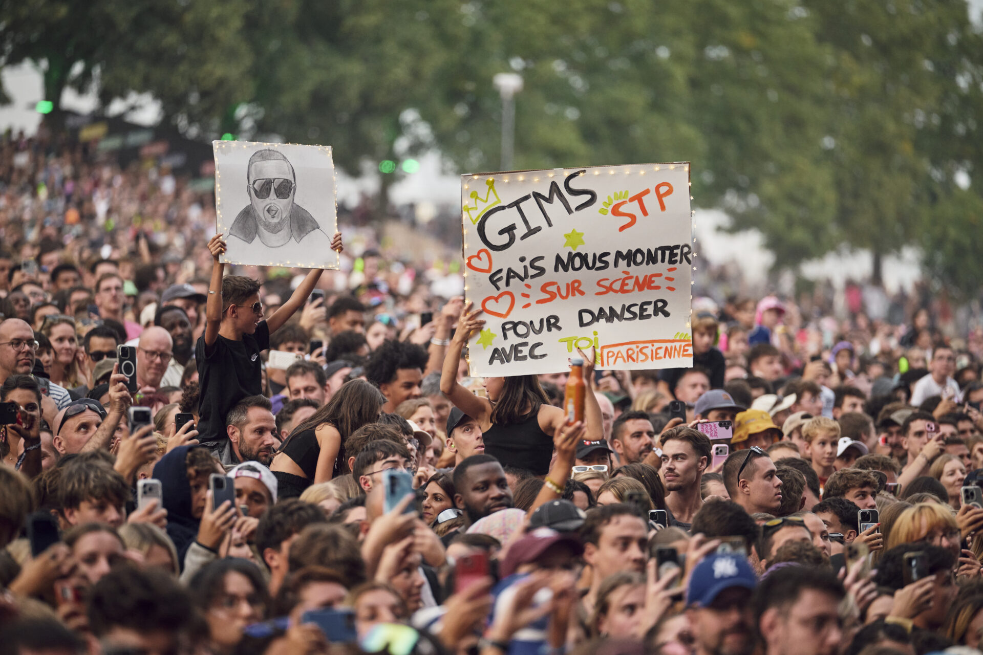 Foule de concert avec pancartes pour GIMS