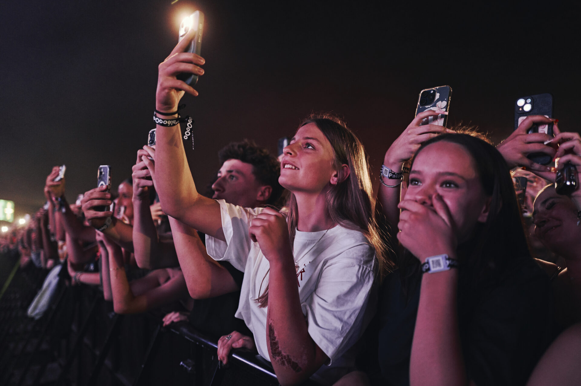 Jeunes au concert filmant avec smartphones allumés