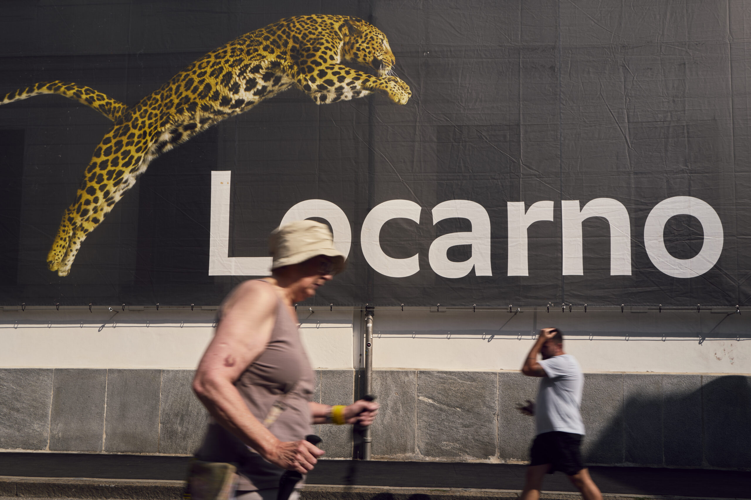 Projection de léopards et passants flous sur façade urbaine