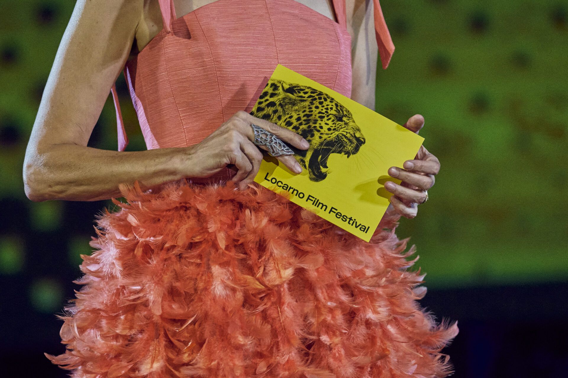 Mains tenant des billets jaunes sur tenue rose à plumes